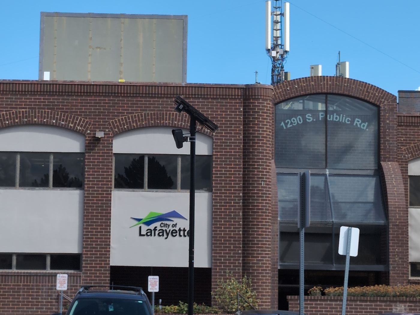 A Flock license plate camera on a black pole in front of Lafayette City Hall